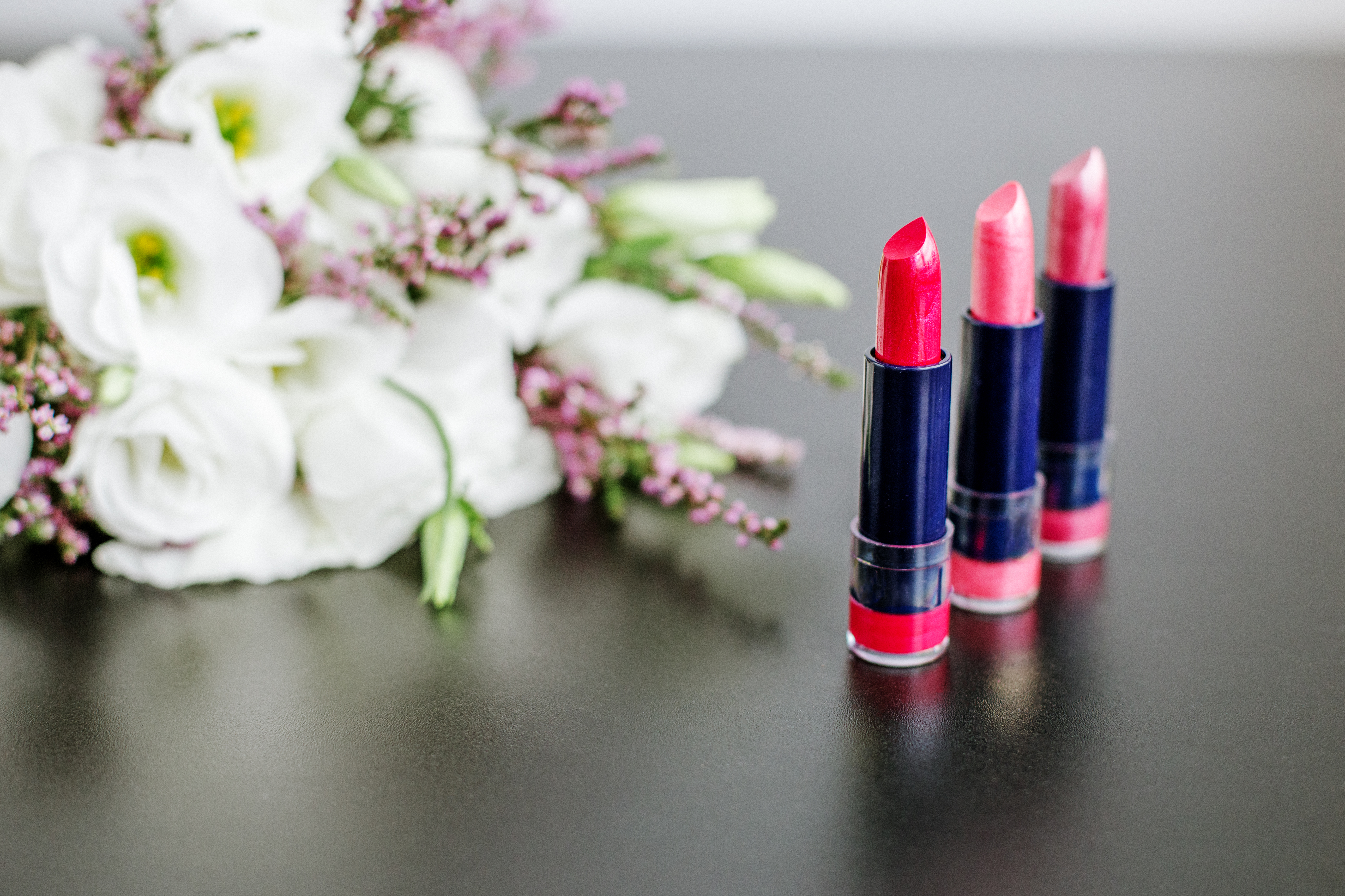 Set of colored lipsticks. Concept of cosmetics and care. Beautiful flowers. Copy space.